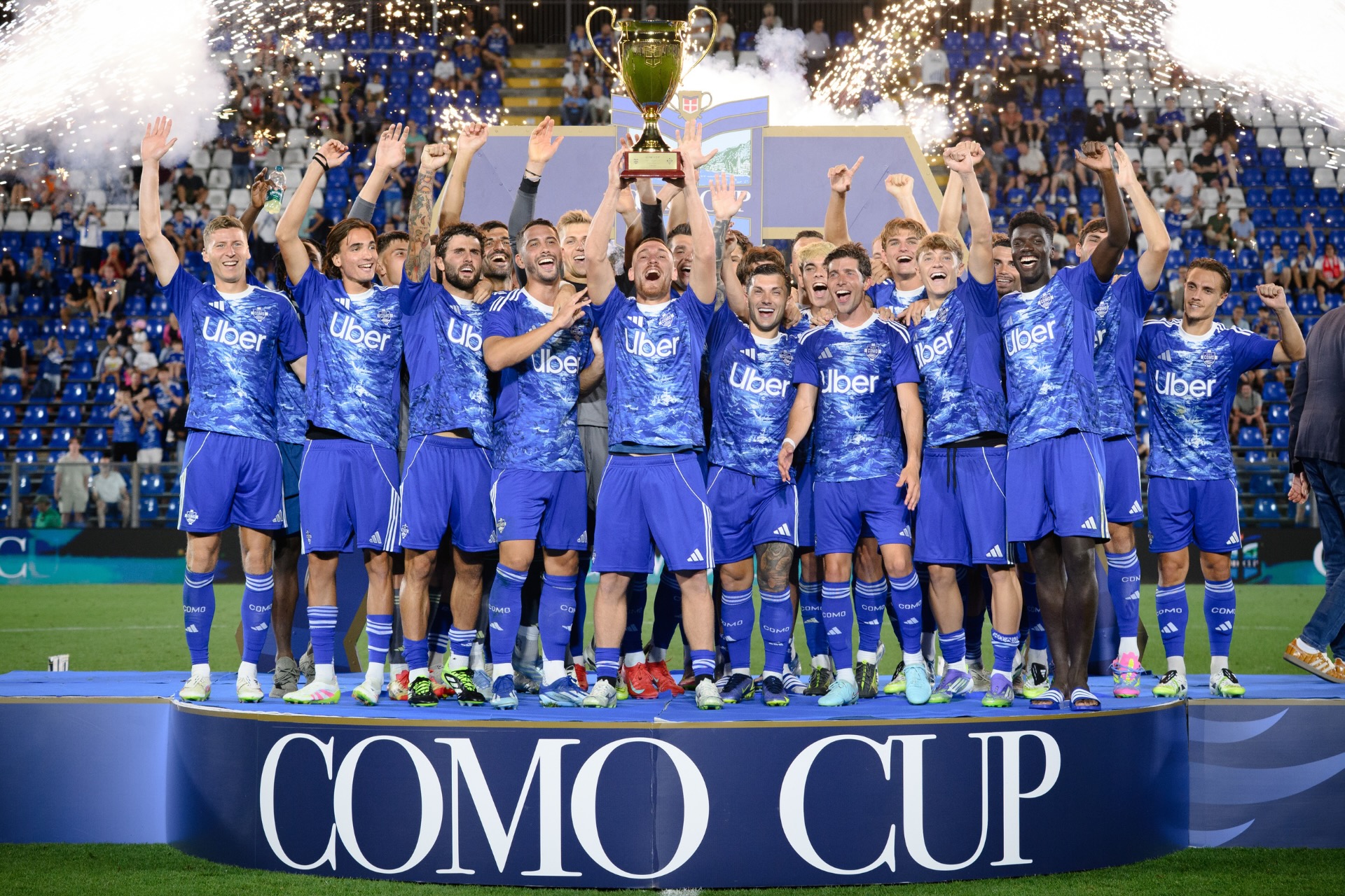 Como 1907 players celebrating with a trophy at Stadio Giuseppe Sinigaglia