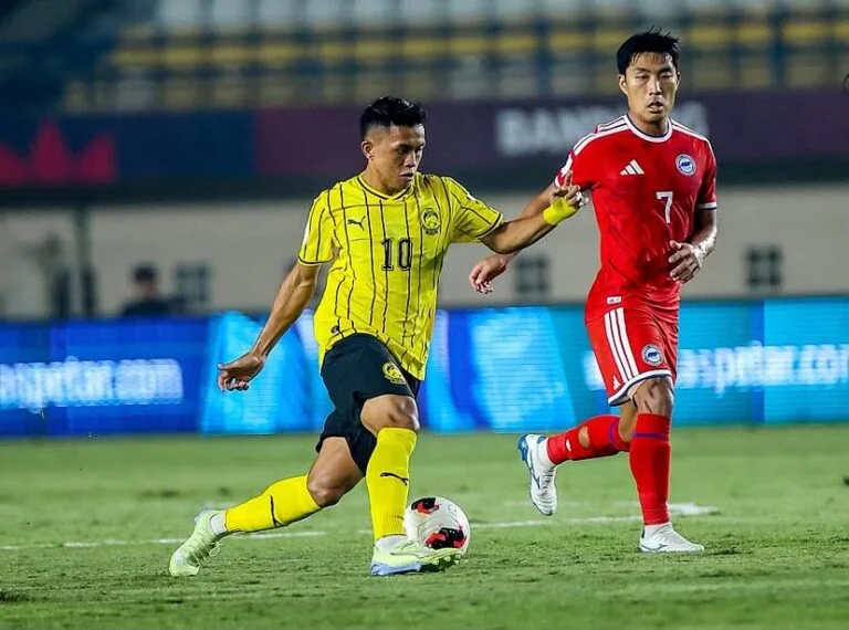 A Malaysia player and a Singapore player challenge for the ball during their FIFA ASEAN Cup 2026 match in Bandung